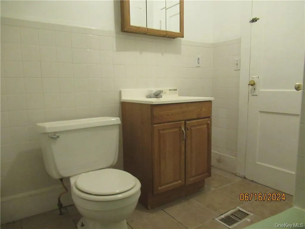 Bathroom with tile floors, vanity, toilet, and tile walls Bathroom with tile floors, vanity, toilet, and tile walls