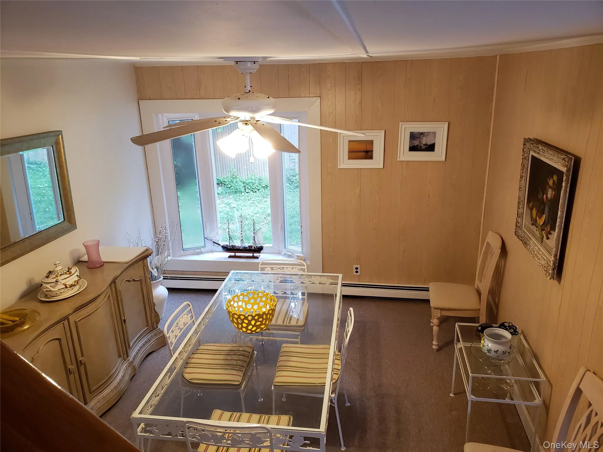 Dining area featuring ceiling fan, wooden walls, and baseboard heating Dining area featuring ceiling fan, wooden walls, and baseboard heating