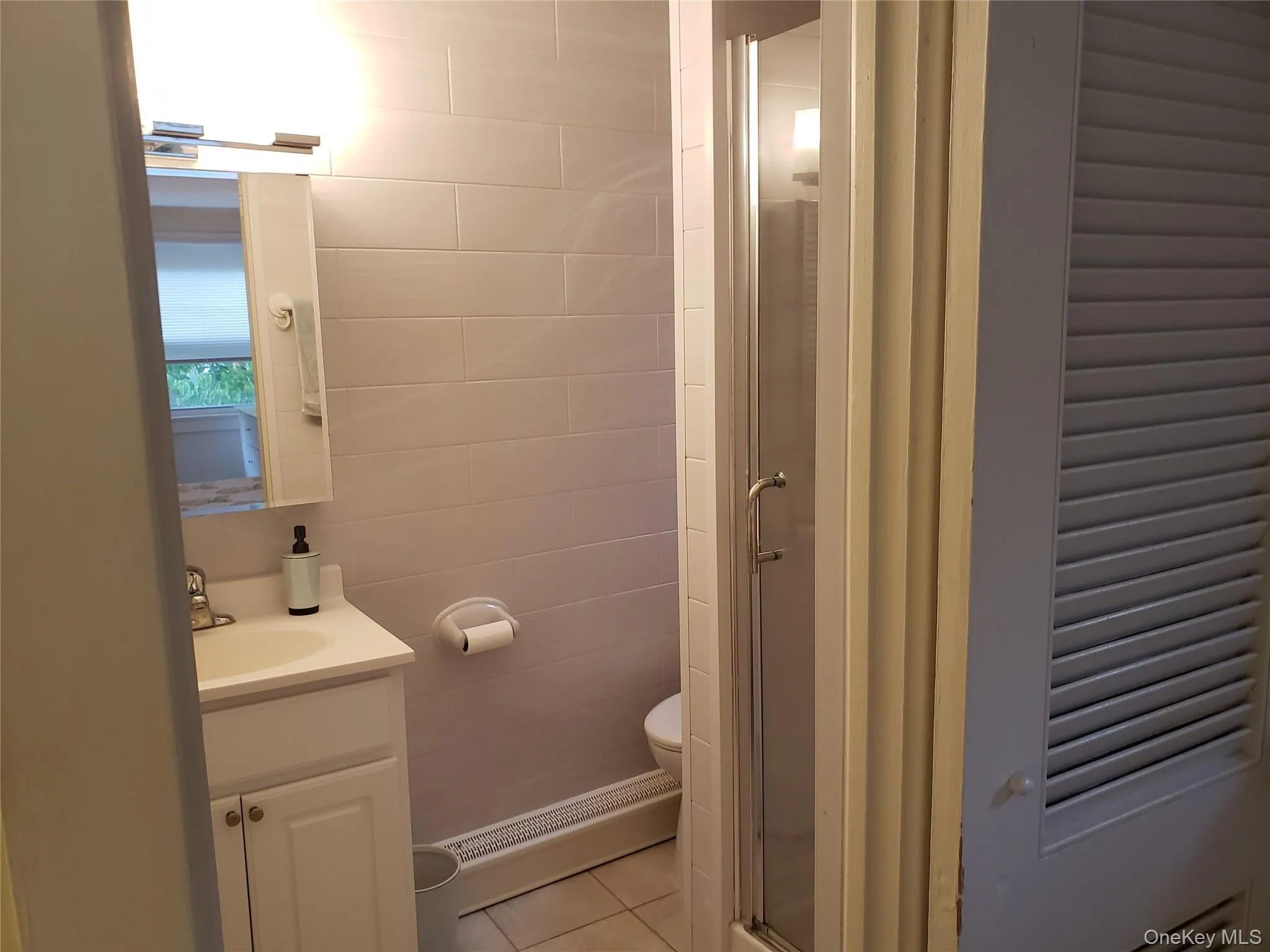 Full bathroom with vanity, a stall shower, tile walls, and tile patterned floors Full bathroom with vanity, a stall shower, tile walls, and tile patterned floors
