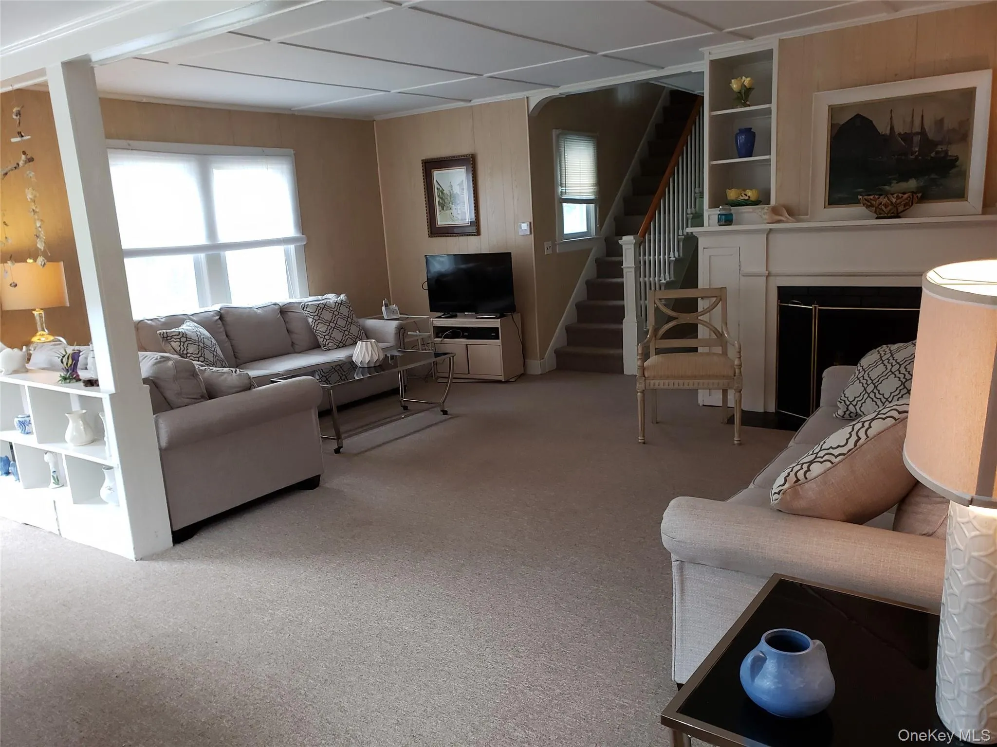 Carpeted living room with stairway, built in shelves, and a fireplace Carpeted living room with stairway, built in shelves, and a fireplace