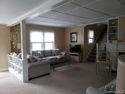 Carpeted living room with plenty of natural light and stairway Carpeted living room with plenty of natural light and stairway