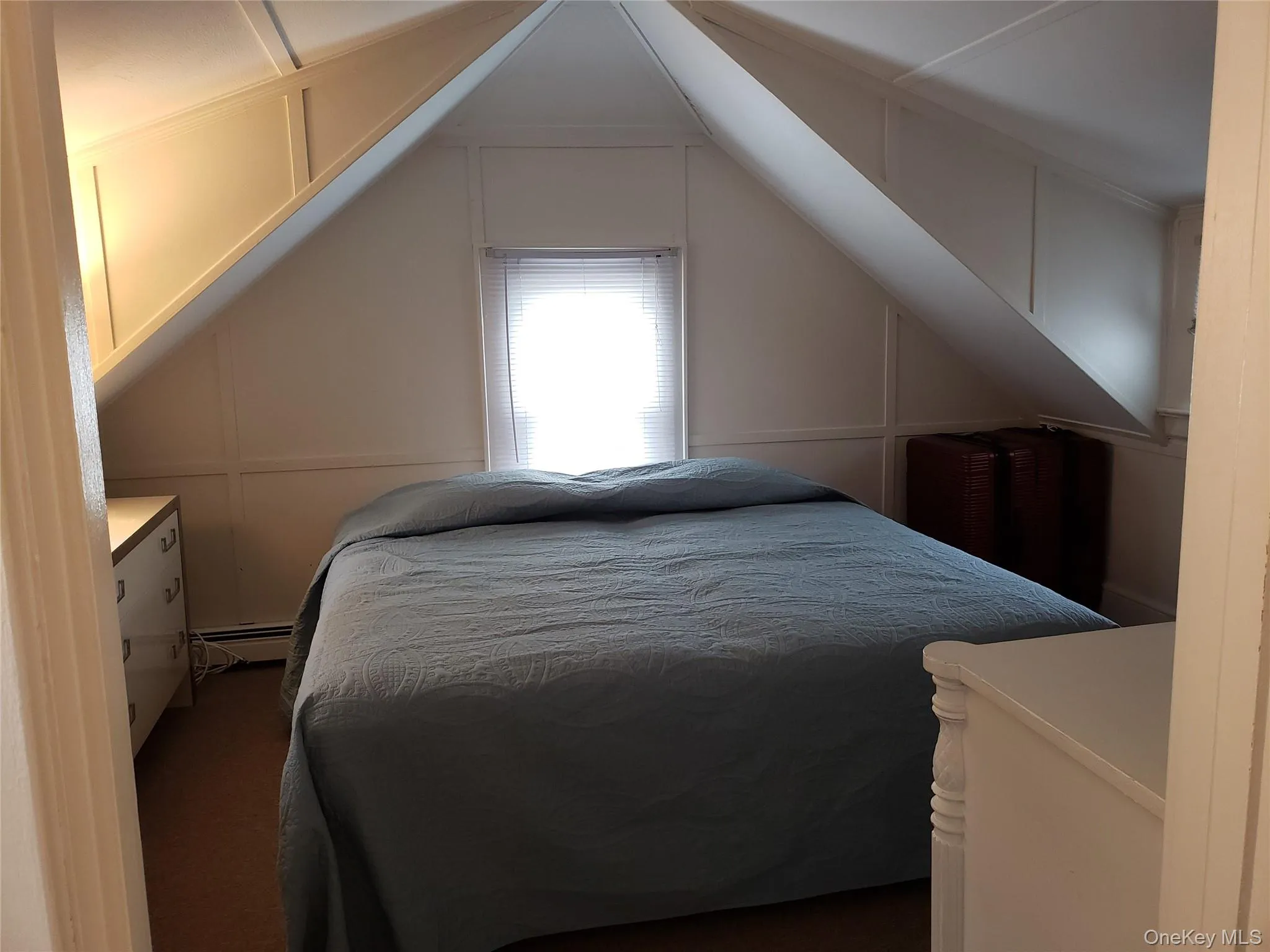 Carpeted bedroom with a decorative wall and a baseboard heating unit Carpeted bedroom with a decorative wall and a baseboard heating unit