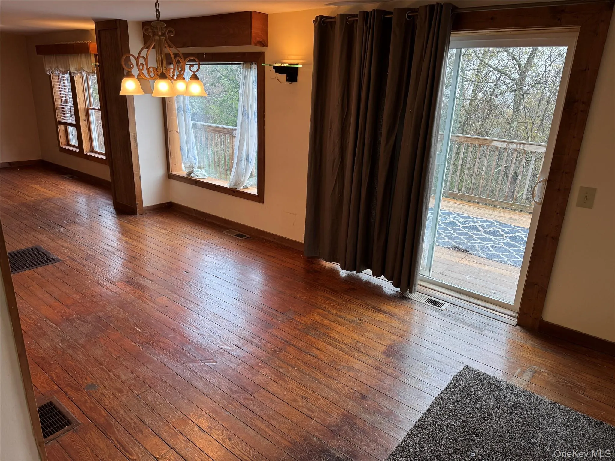This inviting interior space features hardwood floors, large windows, and a sliding glass door providing access to an exterior deck This inviting interior space features hardwood floors, large windows, and a sliding glass door providing access to an exterior deck
