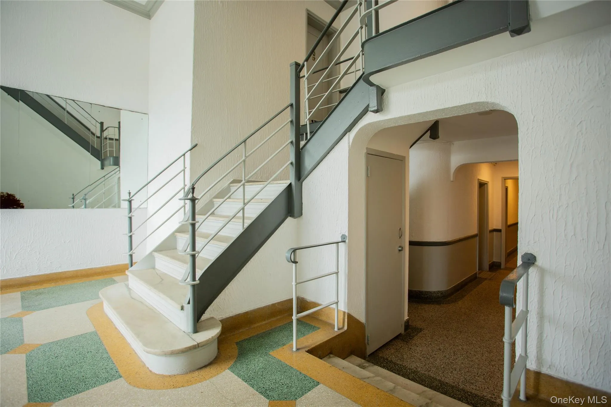 Stairway featuring arched walkways, a high ceiling, and baseboards Stairway featuring arched walkways, a high ceiling, and baseboards
