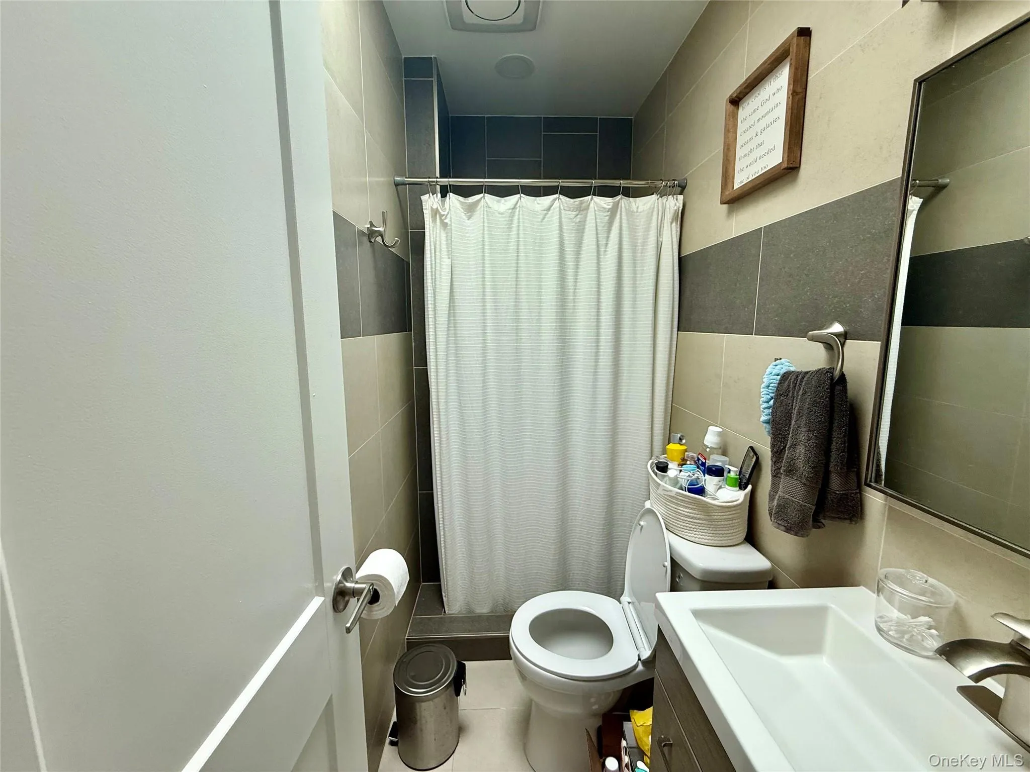 Bathroom with tile walls, tiled shower, toilet, and vanity Bathroom with tile walls, tiled shower, toilet, and vanity