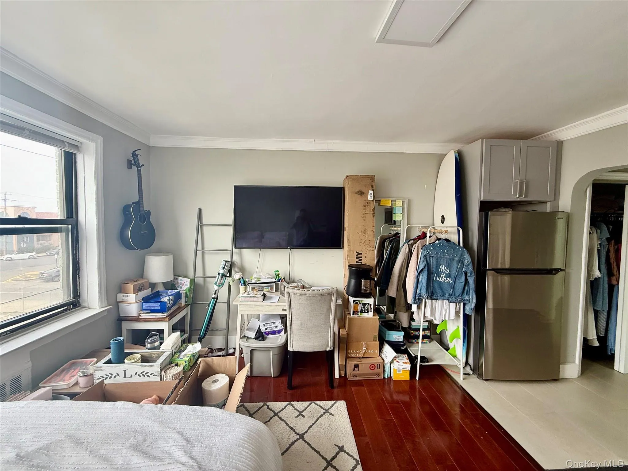 Bedroom with freestanding refrigerator, arched walkways, ornamental molding, and wood finished floors Bedroom with freestanding refrigerator, arched walkways, ornamental molding, and wood finished floors