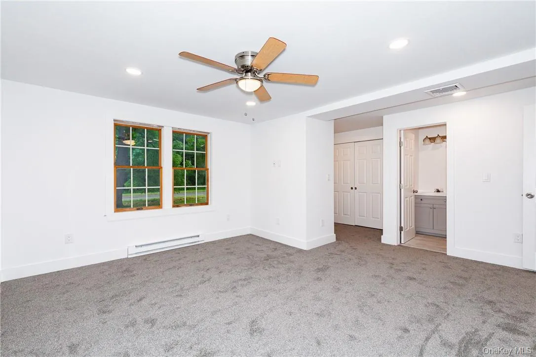 Unfurnished room with ceiling fan, carpet flooring, and baseboard heating Unfurnished room with ceiling fan, carpet flooring, and baseboard heating