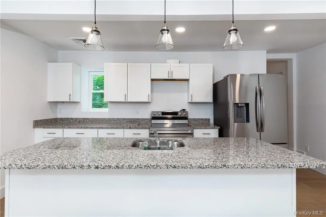 Kitchen featuring stainless steel appliances, sink, hardwood / wood-style flooring, and a kitchen island with sink Kitchen featuring stainless steel appliances, sink, hardwood / wood-style flooring, and a kitchen island with sink