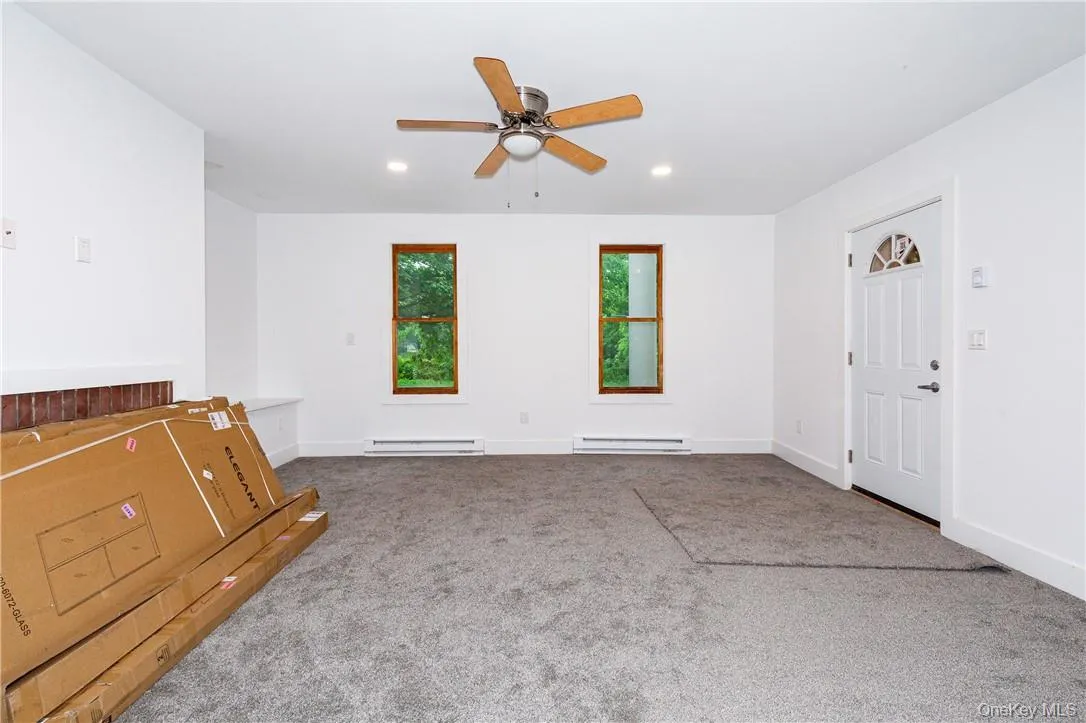 Carpeted spare room with a baseboard heating unit and ceiling fan Carpeted spare room with a baseboard heating unit and ceiling fan