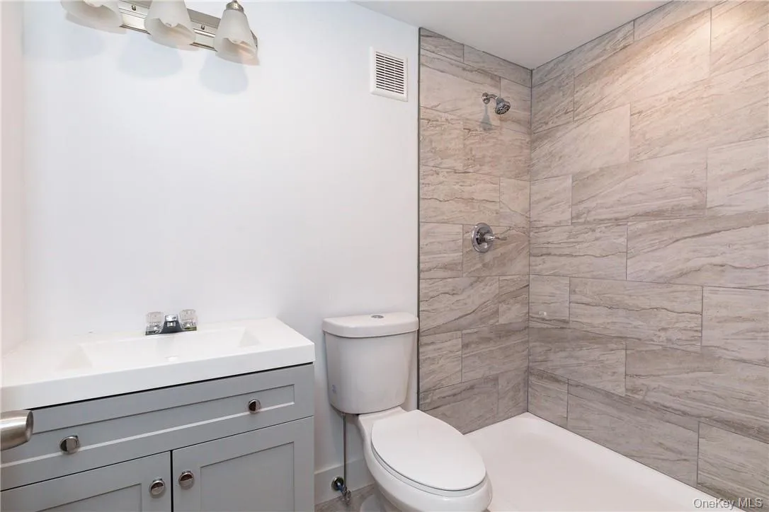 Bathroom with a tile shower, toilet, and vanity Bathroom with a tile shower, toilet, and vanity