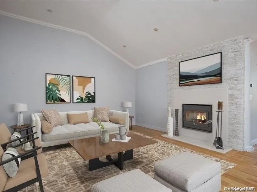 Living area featuring ornamental molding, a large fireplace, wood finished floors, and vaulted ceiling Living area featuring ornamental molding, a large fireplace, wood finished floors, and vaulted ceiling