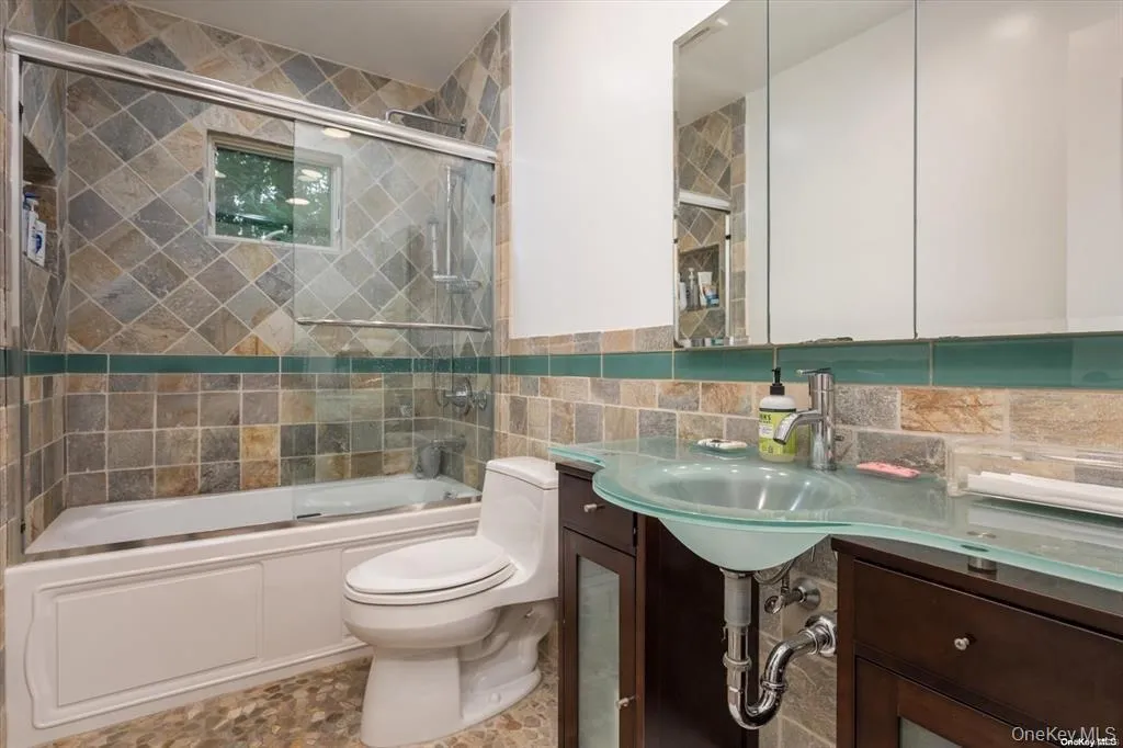 Bathroom featuring enclosed tub / shower combo and tile walls Bathroom featuring enclosed tub / shower combo and tile walls