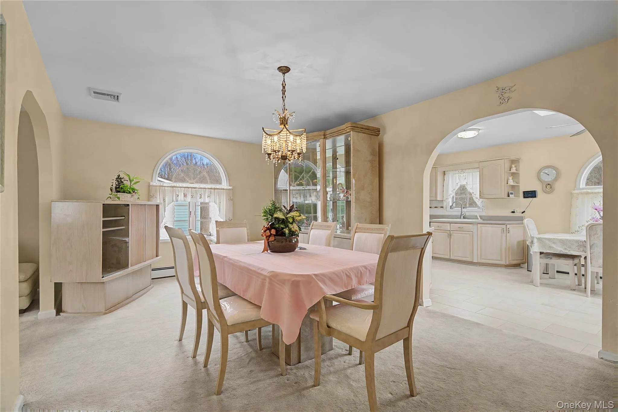 Dining area with arched walkways, light colored carpet, and hanging lights Dining area with arched walkways, light colored carpet, and hanging lights