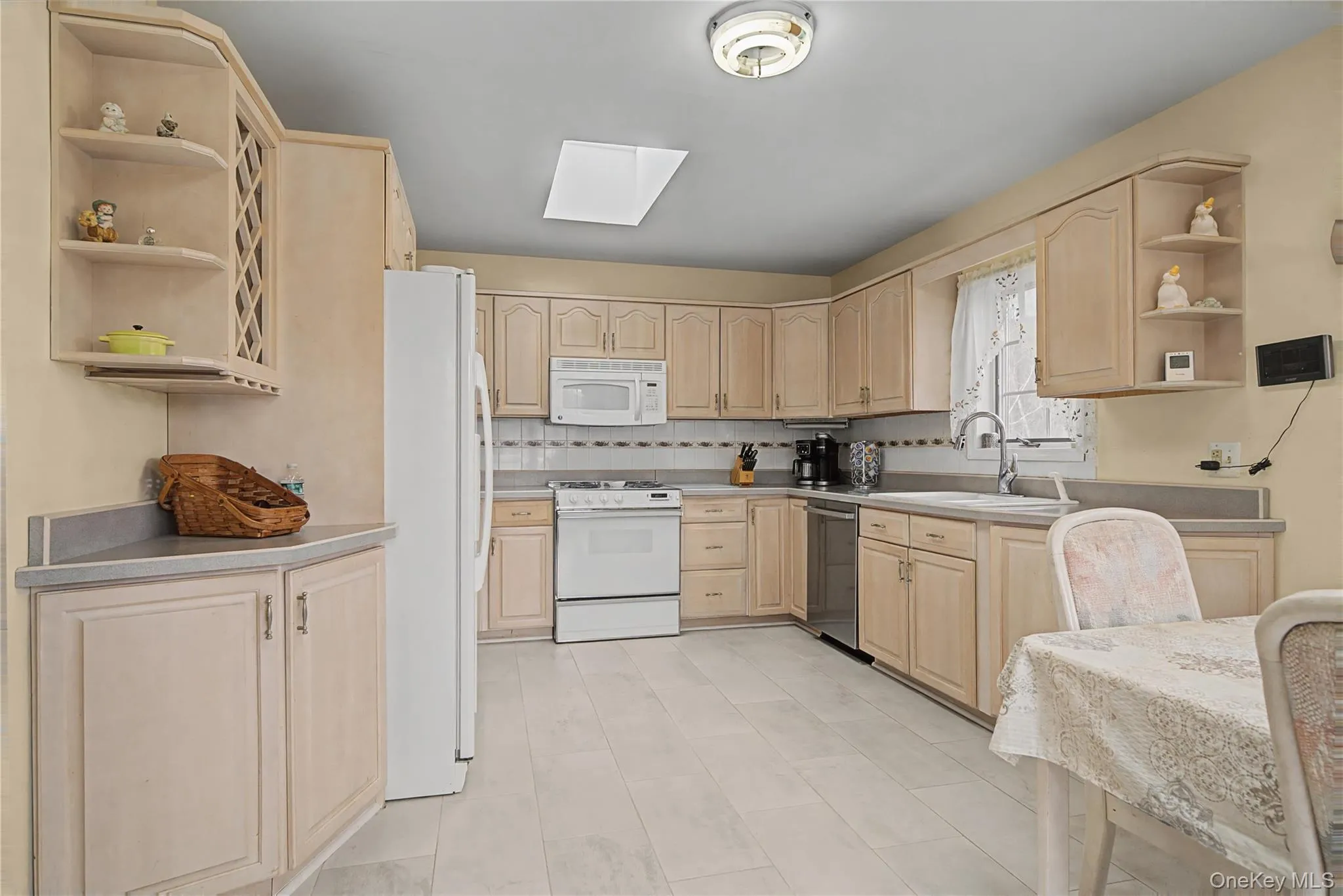 Kitchen featuring open shelves, light wood finish cabinets, a skylight, and white appliances Kitchen featuring open shelves, light wood finish cabinets, a skylight, and white appliances
