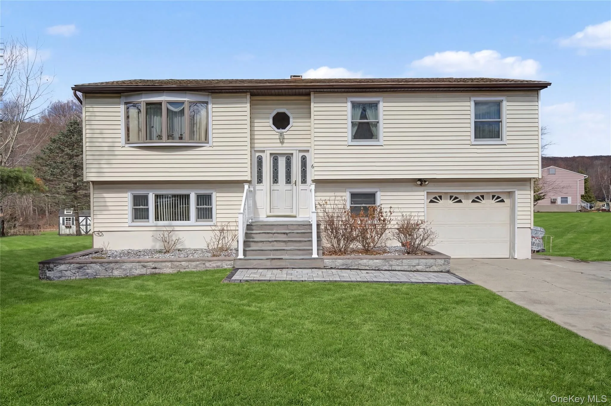 Bi-level home featuring a front lawn, a garage, and concrete driveway Bi-level home featuring a front lawn, a garage, and concrete driveway
