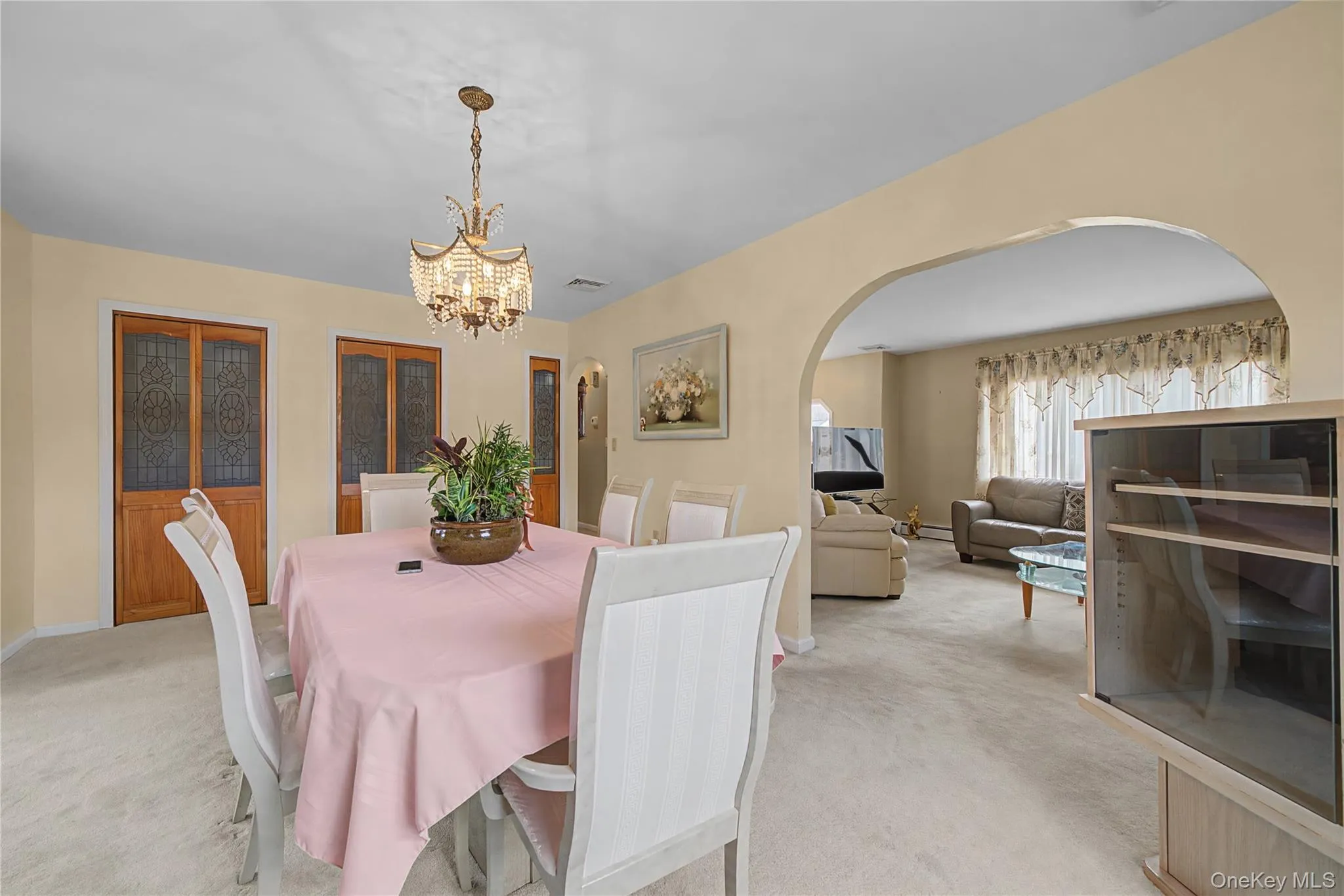 Dining room with light colored carpet, arched walkways, and hanging lights Dining room with light colored carpet, arched walkways, and hanging lights