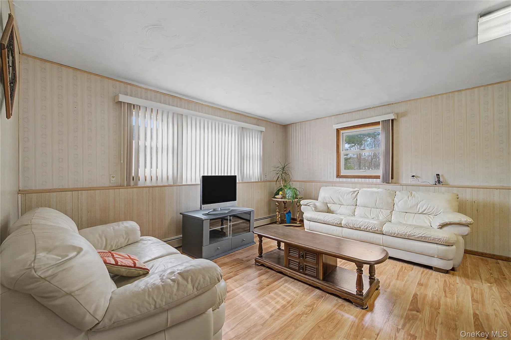 Living area featuring wallpapered walls, wood finished floors, and a baseboard radiator Living area featuring wallpapered walls, wood finished floors, and a baseboard radiator