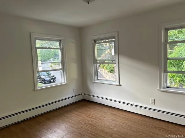 Spare room with baseboard heating and dark wood-type flooring Spare room with baseboard heating and dark wood-type flooring