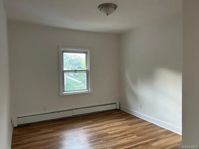bedroom featuring a baseboard radiator and hardwood / wood-style floors bedroom featuring a baseboard radiator and hardwood / wood-style floors