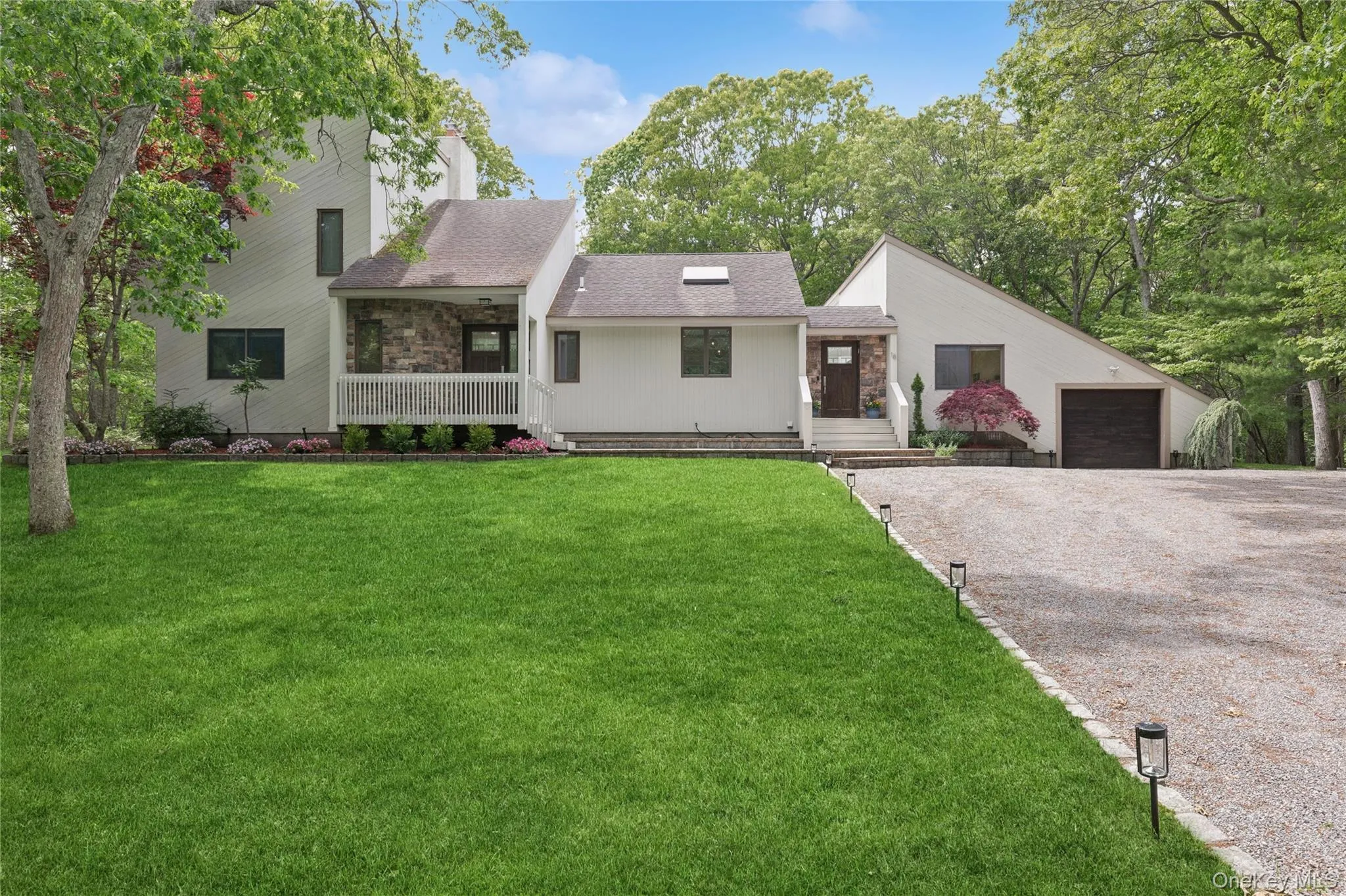 View of front facade featuring driveway, covered porch, a front lawn, and a shingled roof View of front facade featuring driveway, covered porch, a front lawn, and a shingled roof