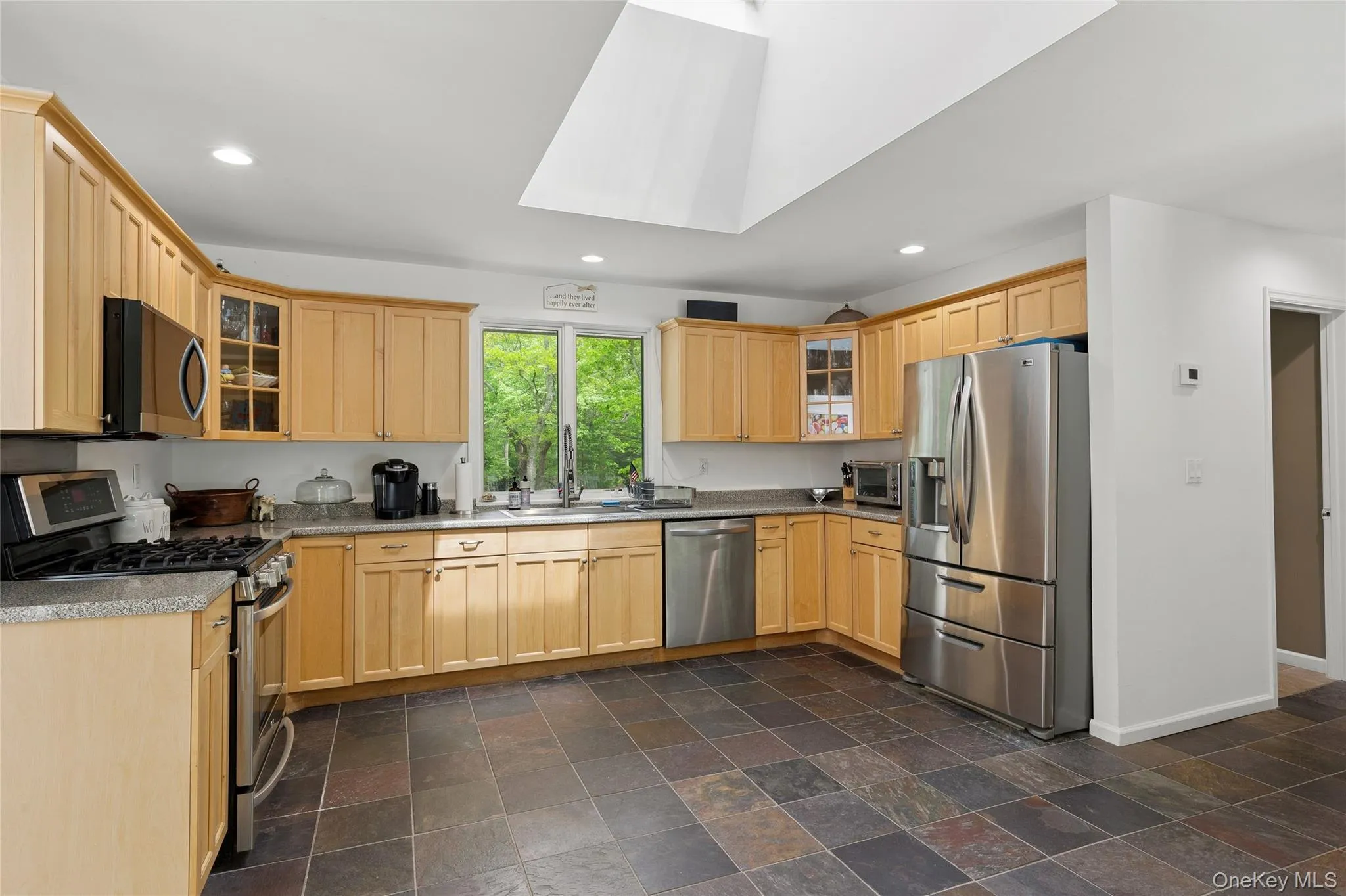 Kitchen featuring stainless steel appliances, baseboards, light brown cabinetry, recessed lighting, and a sink Kitchen featuring stainless steel appliances, baseboards, light brown cabinetry, recessed lighting, and a sink