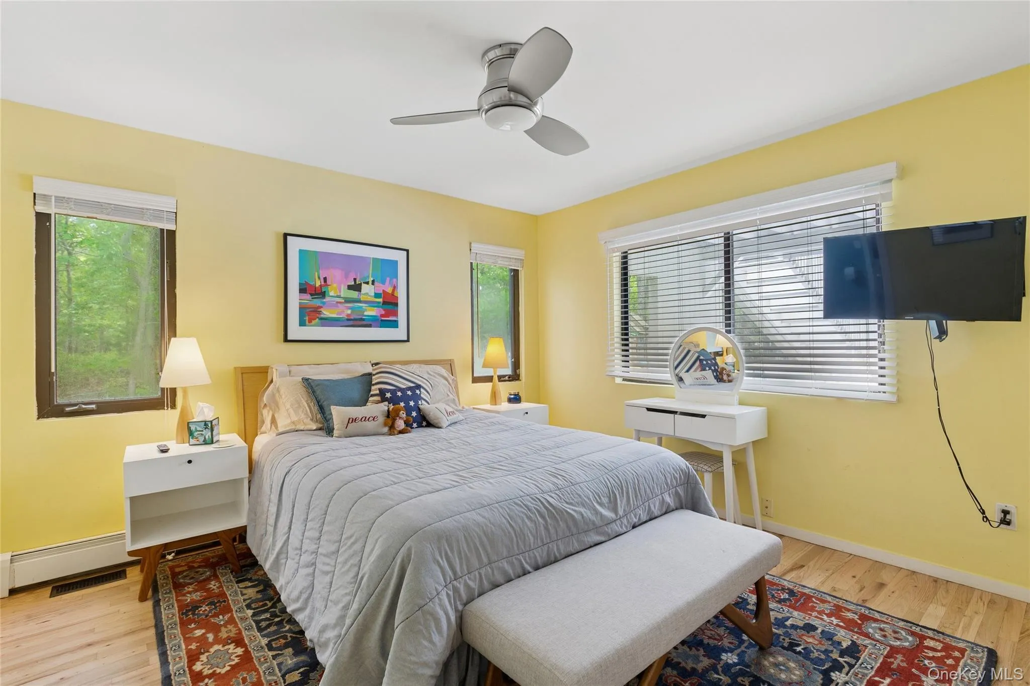 Bedroom featuring wood finished floors, a baseboard radiator, baseboards, and a ceiling fan Bedroom featuring wood finished floors, a baseboard radiator, baseboards, and a ceiling fan