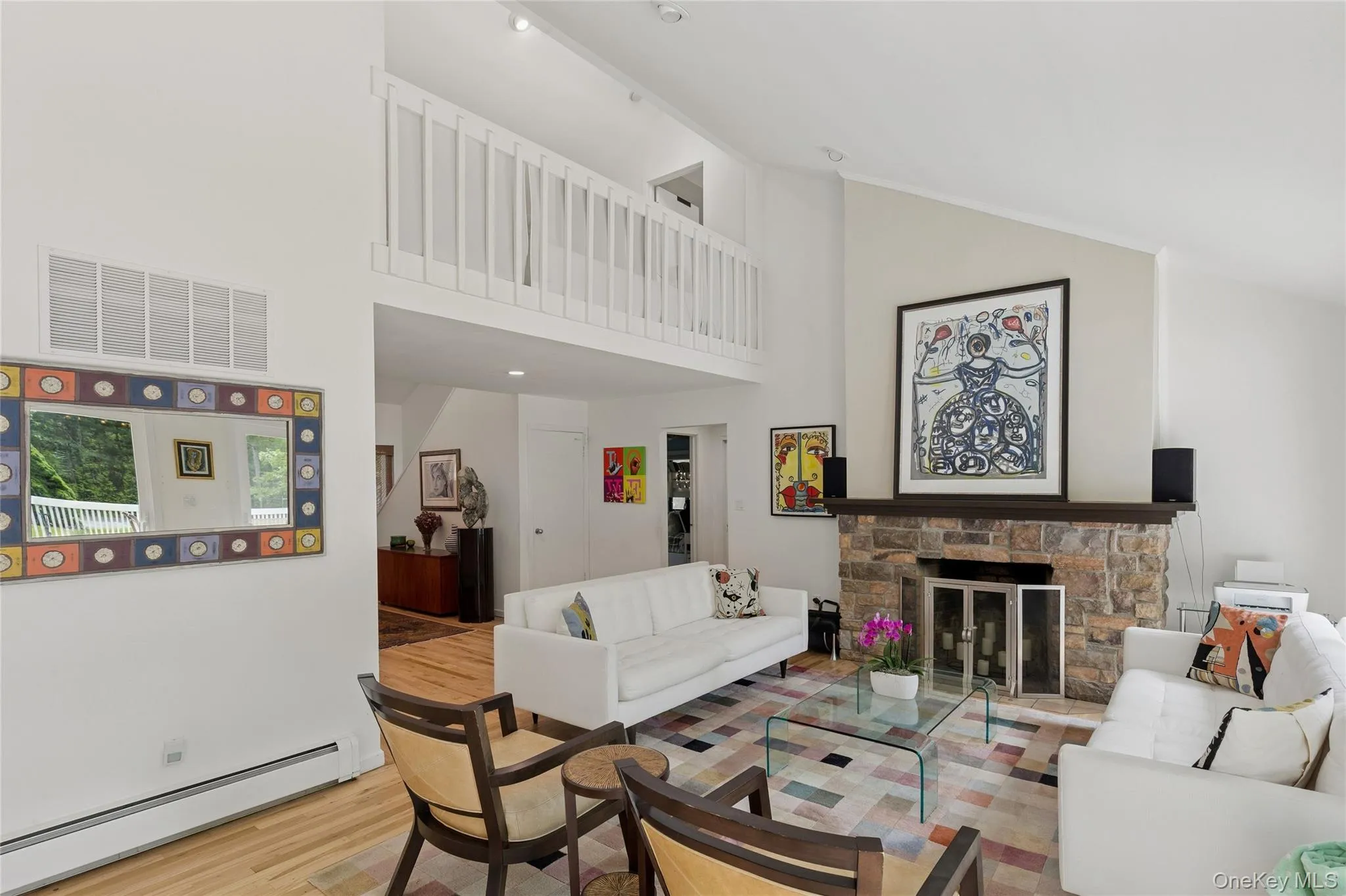 Living area featuring a baseboard heating unit, high vaulted ceiling, wood finished floors, and a fireplace Living area featuring a baseboard heating unit, high vaulted ceiling, wood finished floors, and a fireplace