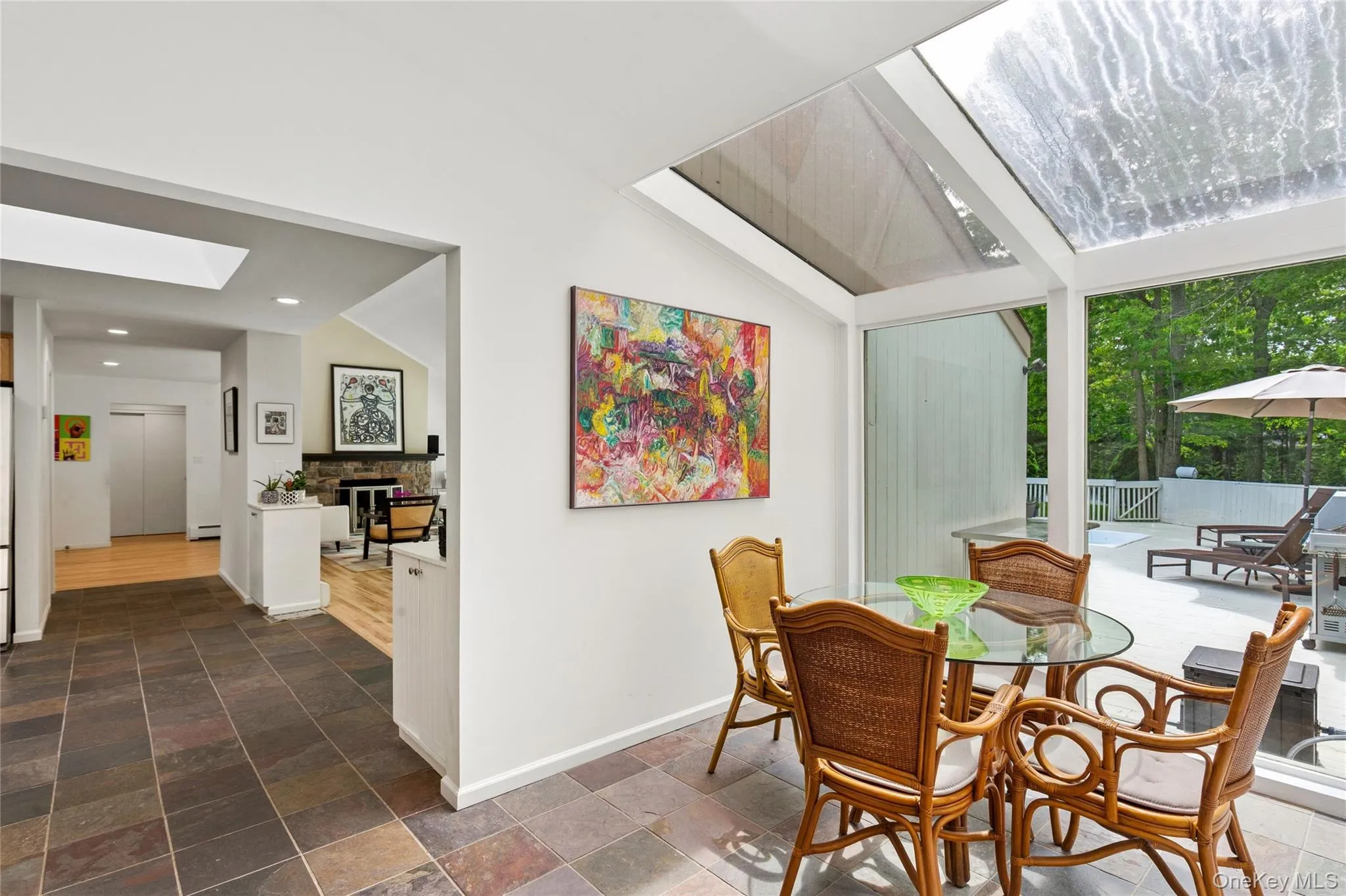 Dining space featuring a skylight, stone tile floors, a stone fireplace, recessed lighting, and a towering ceiling Dining space featuring a skylight, stone tile floors, a stone fireplace, recessed lighting, and a towering ceiling