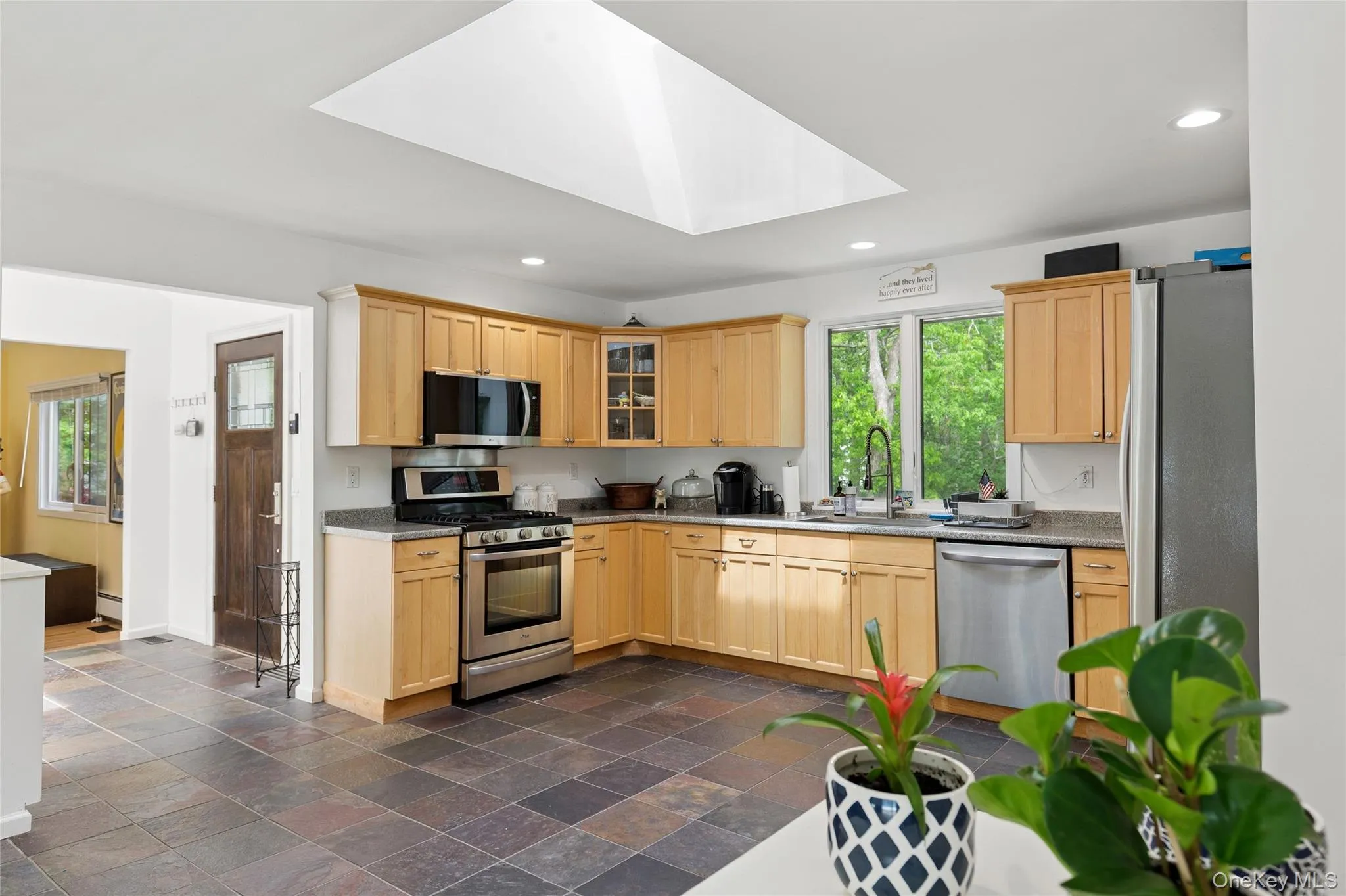 Kitchen with appliances with stainless steel finishes, a sink, a skylight, recessed lighting, and light brown cabinets Kitchen with appliances with stainless steel finishes, a sink, a skylight, recessed lighting, and light brown cabinets
