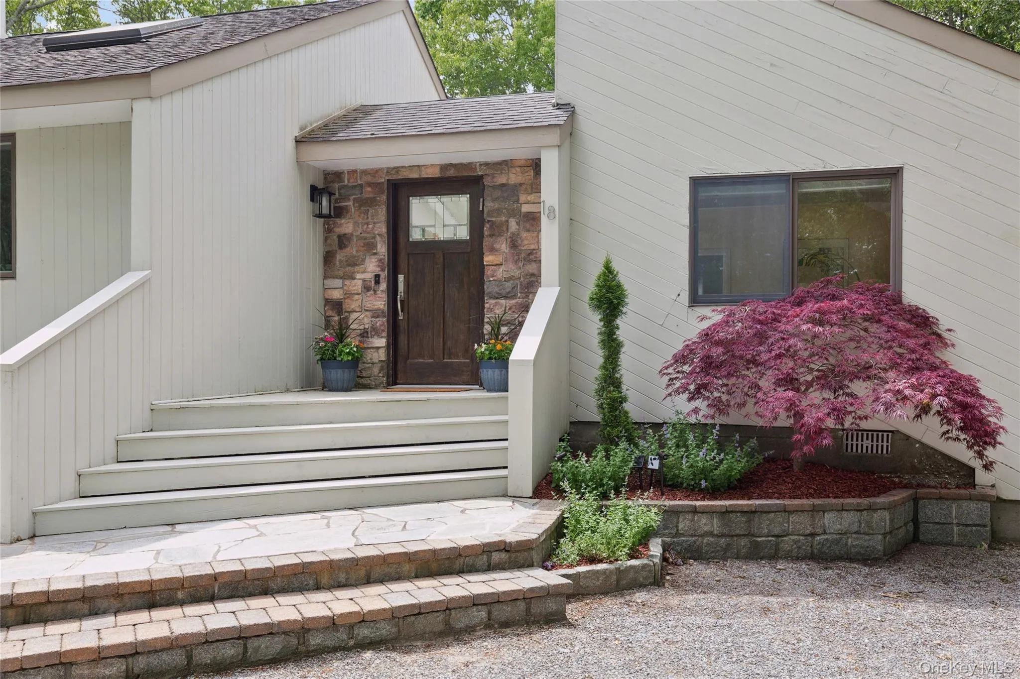 Property entrance featuring solar panels, roof with shingles, and stone siding Property entrance featuring solar panels, roof with shingles, and stone siding