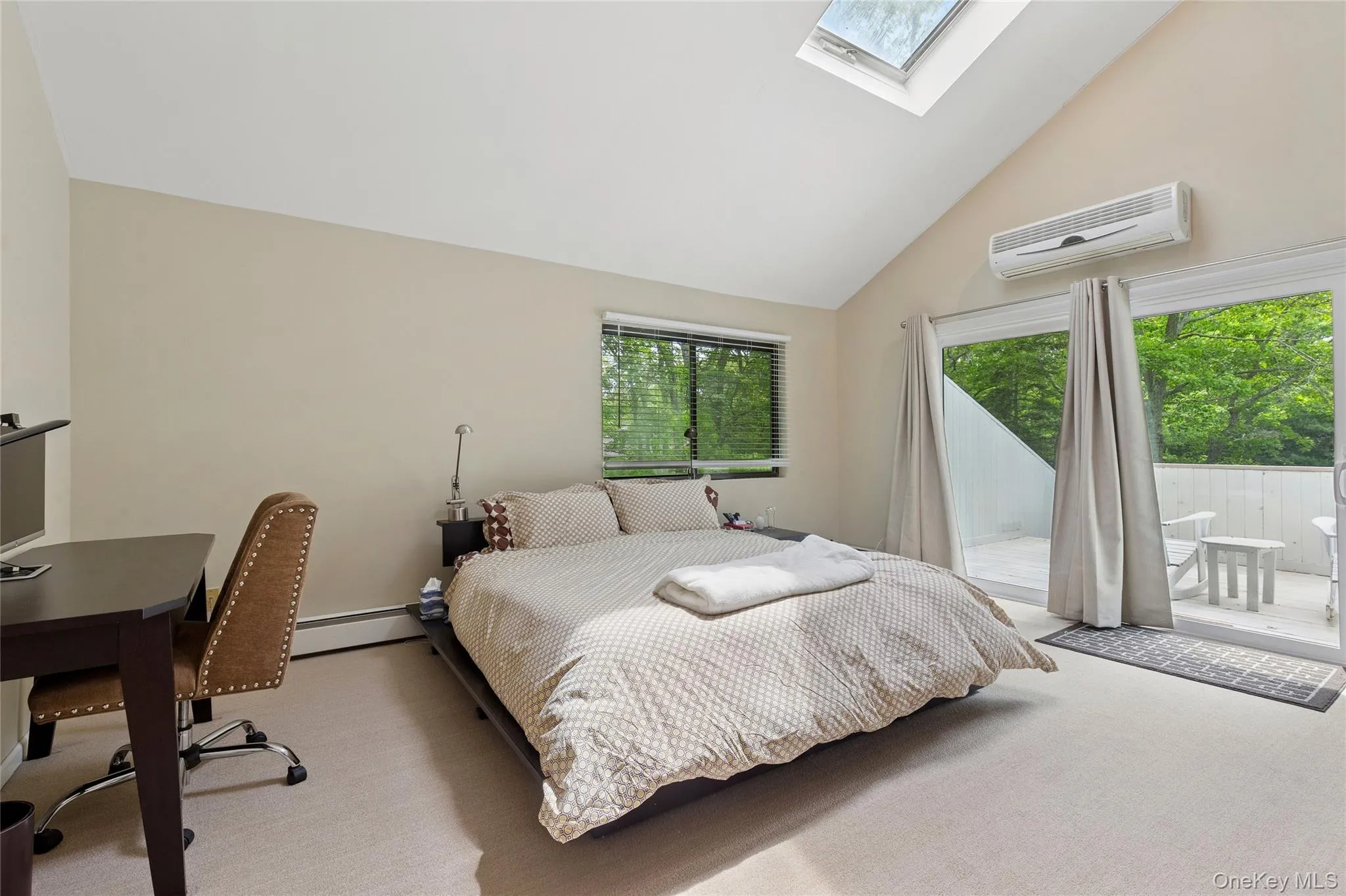 Bedroom featuring a wall mounted air conditioner, a skylight, access to exterior, a baseboard radiator, and carpet Bedroom featuring a wall mounted air conditioner, a skylight, access to exterior, a baseboard radiator, and carpet