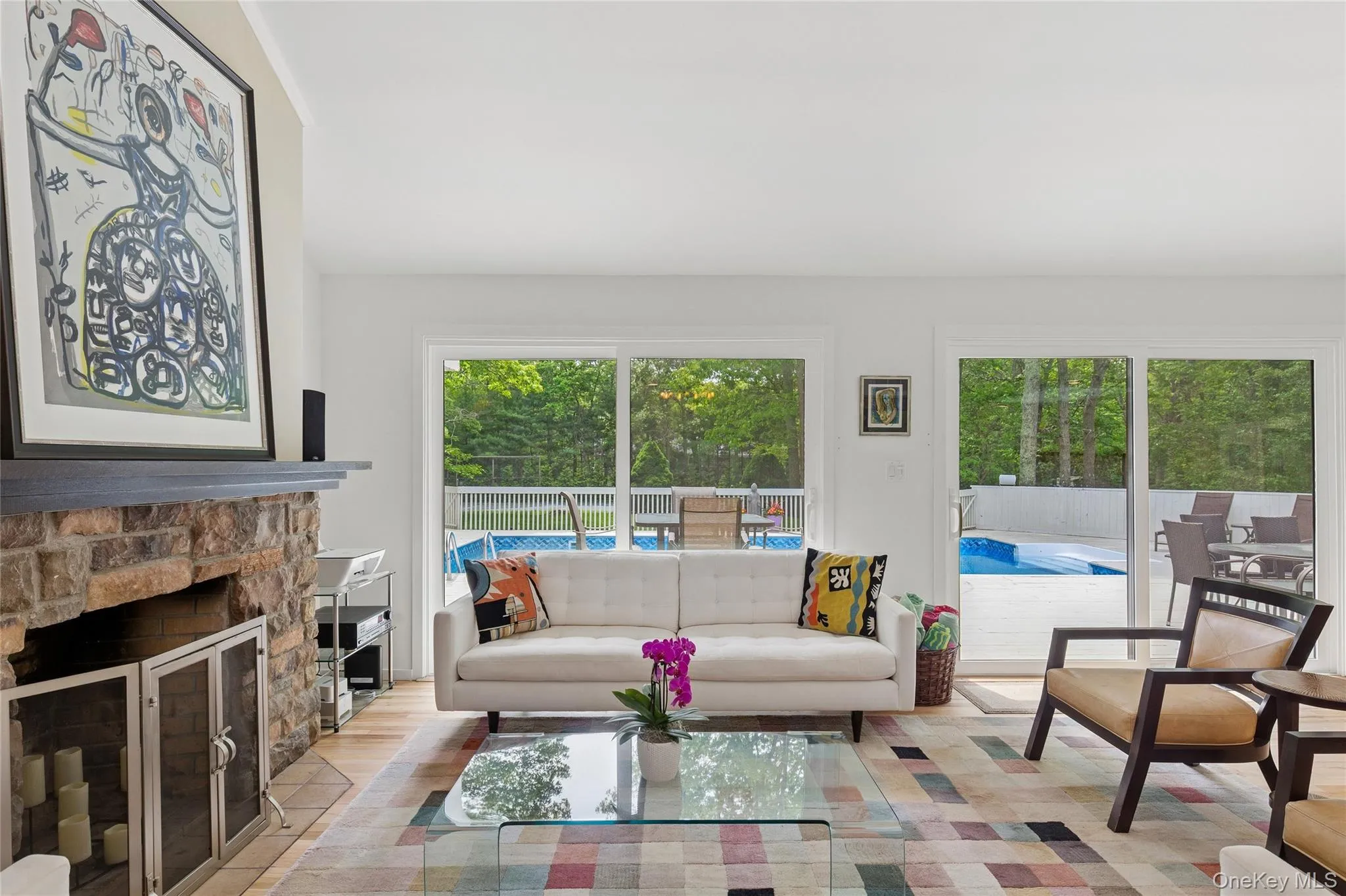 Living room featuring plenty of natural light, wood finished floors, and a stone fireplace Living room featuring plenty of natural light, wood finished floors, and a stone fireplace