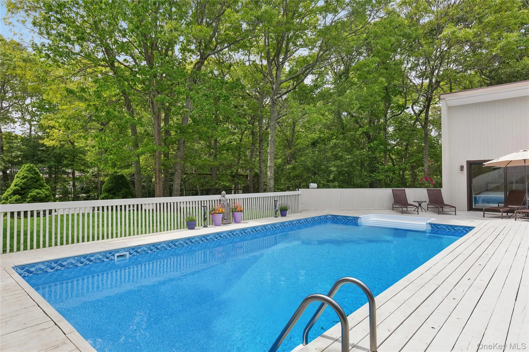 View of swimming pool with a wooden deck and view of wooded area View of swimming pool with a wooden deck and view of wooded area