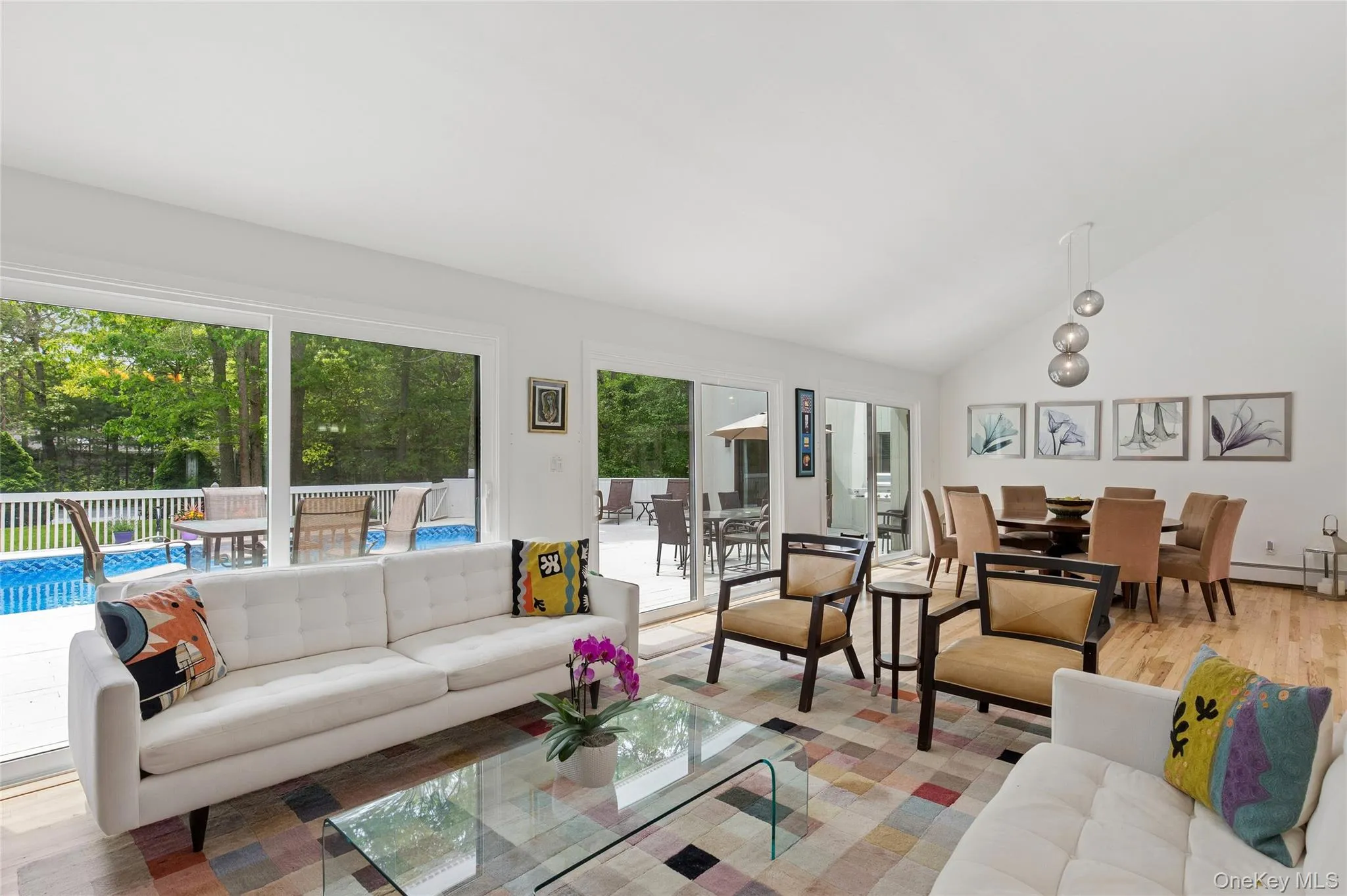 Living room with lofted ceiling, wood finished floors, and baseboard heating Living room with lofted ceiling, wood finished floors, and baseboard heating