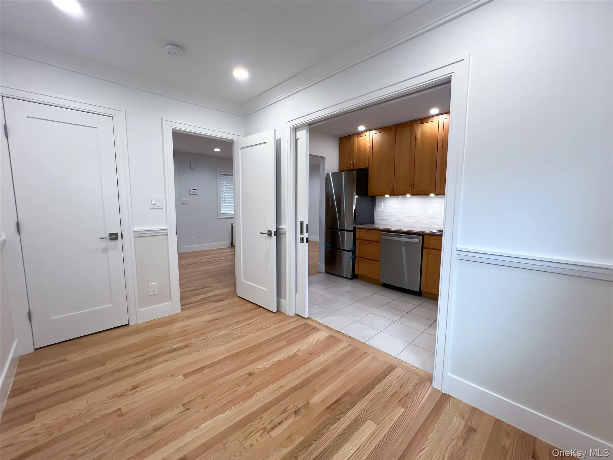 Kitchen featuring brown cabinets, tasteful backsplash, light wood finished floors, appliances with stainless steel finishes, and ornamental molding Kitchen featuring brown cabinets, tasteful backsplash, light wood finished floors, appliances with stainless steel finishes, and ornamental molding
