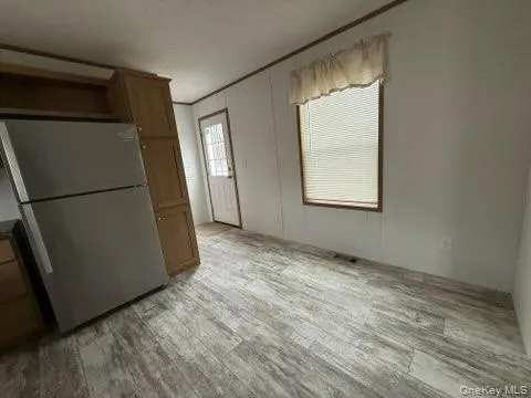 Kitchen with brown cabinets, freestanding refrigerator, and light wood-type flooring Kitchen with brown cabinets, freestanding refrigerator, and light wood-type flooring
