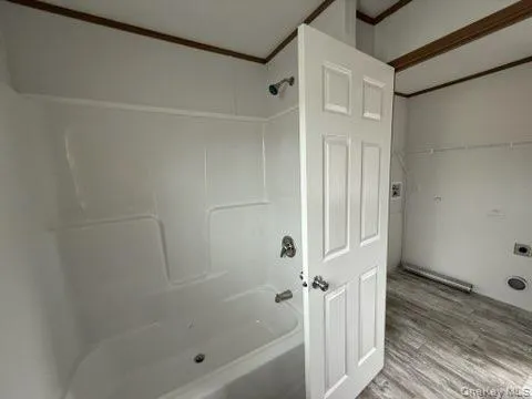 Bathroom featuring bathtub / shower combination and wood finished floors Bathroom featuring bathtub / shower combination and wood finished floors