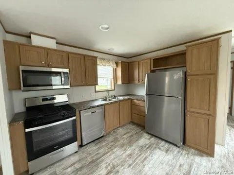 Kitchen with dark countertops, open shelves, light wood-type flooring, a sink, and stainless steel appliances Kitchen with dark countertops, open shelves, light wood-type flooring, a sink, and stainless steel appliances