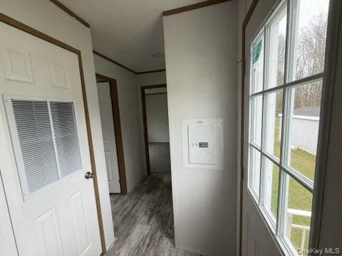 Hallway featuring light wood-style floors, crown molding, electric panel, and a heating unit Hallway featuring light wood-style floors, crown molding, electric panel, and a heating unit