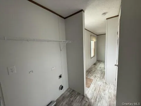 Laundry room with electric dryer hookup, ornamental molding, wood finished floors, and laundry area Laundry room with electric dryer hookup, ornamental molding, wood finished floors, and laundry area