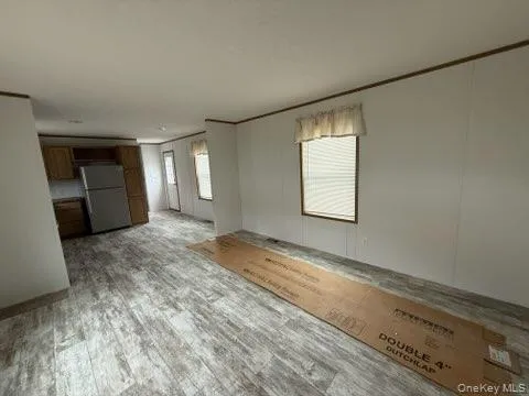 Unfurnished living room with ornamental molding and light wood-style flooring Unfurnished living room with ornamental molding and light wood-style flooring