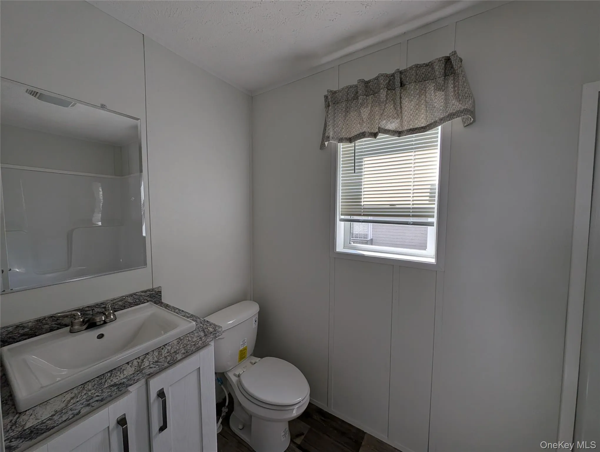 Bathroom featuring vanity, visible vents, wood finished floors, toilet, and walk in shower Bathroom featuring vanity, visible vents, wood finished floors, toilet, and walk in shower