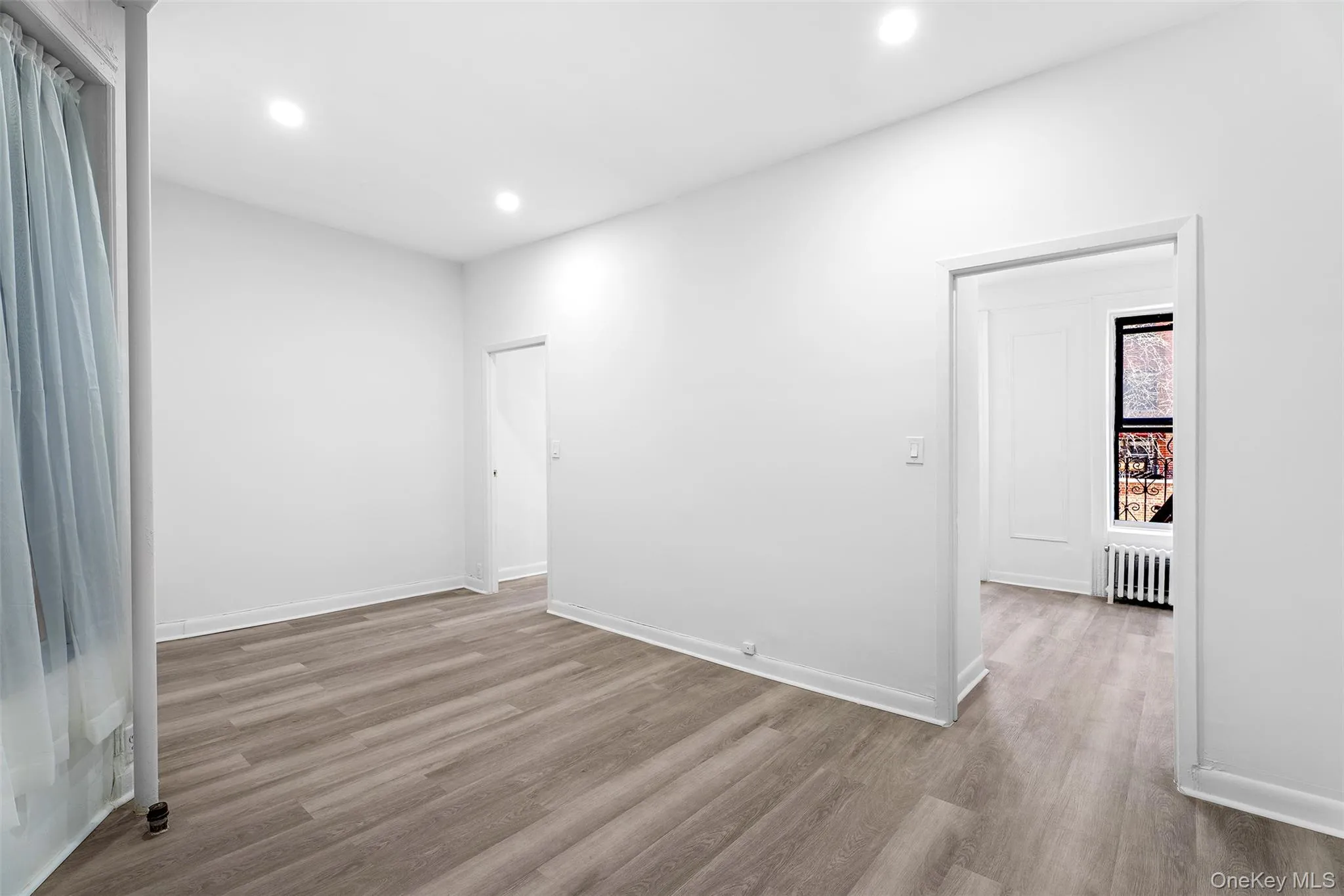 Spare room featuring light wood finished floors, radiator heating unit, and recessed lighting Spare room featuring light wood finished floors, radiator heating unit, and recessed lighting