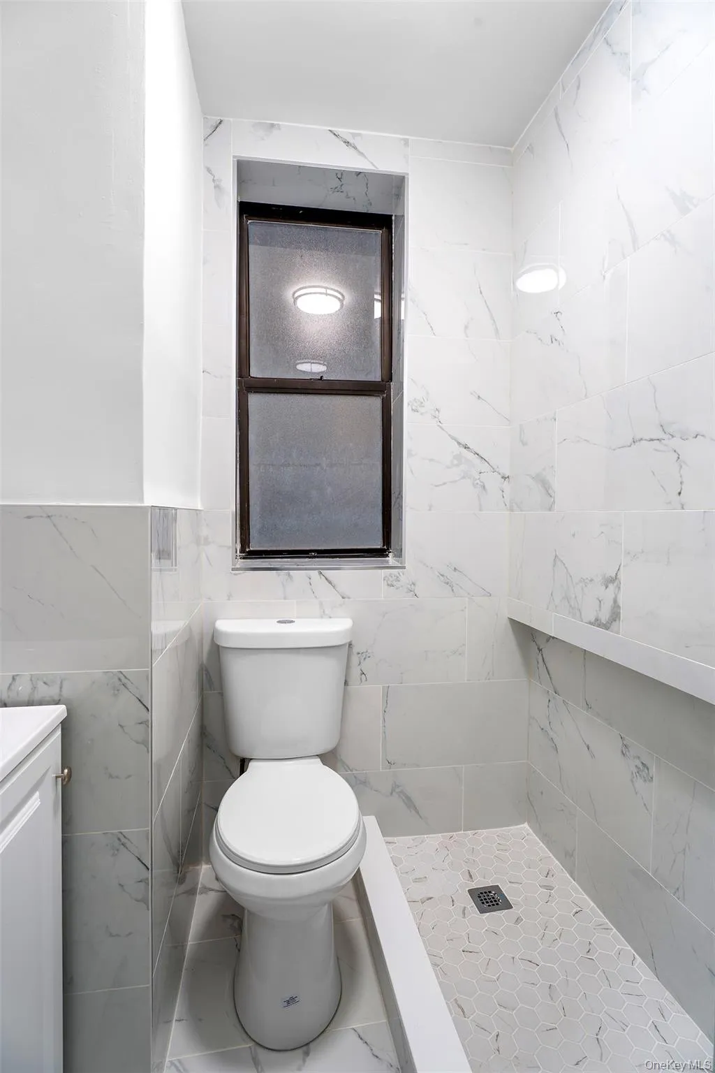 Bathroom featuring vanity, a marble finish shower, tile walls, and marble finish floors Bathroom featuring vanity, a marble finish shower, tile walls, and marble finish floors