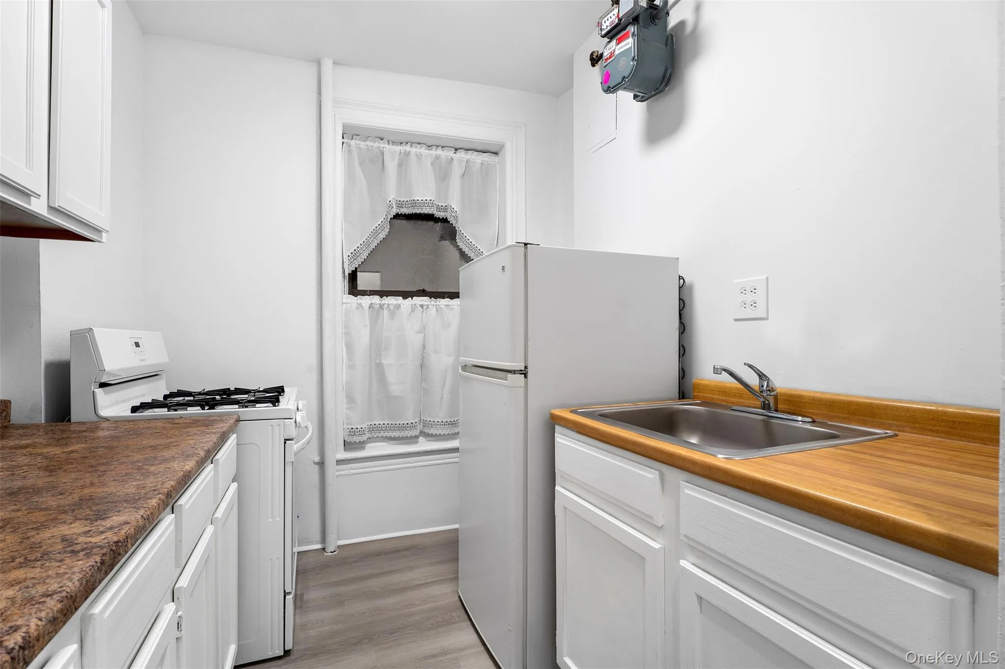 Kitchen with white appliances, white cabinetry, and light wood-style flooring Kitchen with white appliances, white cabinetry, and light wood-style flooring