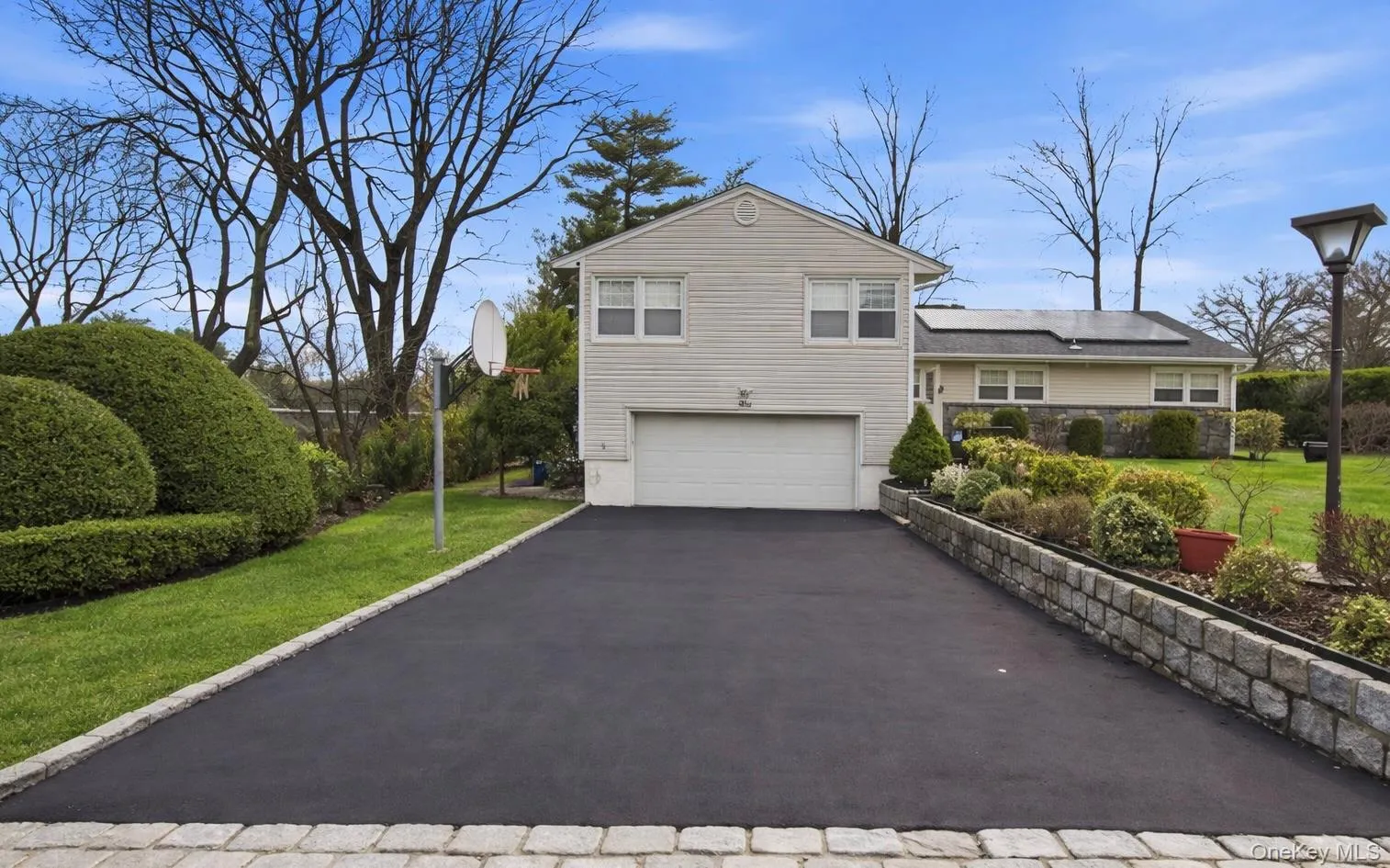 Tri-level home with an attached garage, driveway, and a front lawn Tri-level home with an attached garage, driveway, and a front lawn