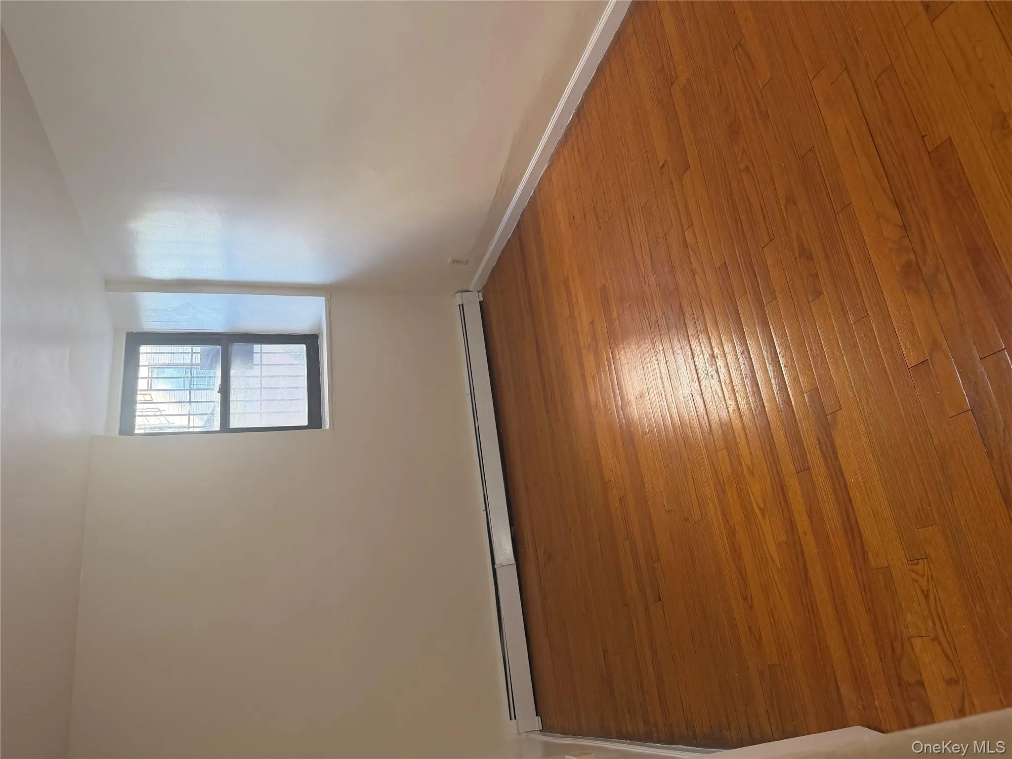 Empty room with a baseboard radiator and hardwood / wood-style floors Empty room with a baseboard radiator and hardwood / wood-style floors