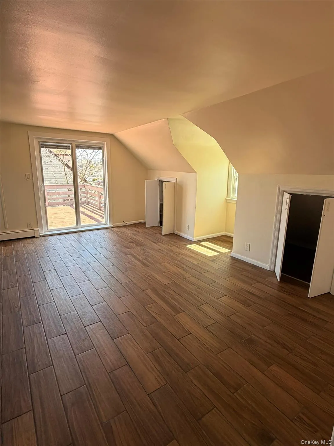 Bonus room with wood tiled floors, lofted ceiling, and a baseboard heating unit. Bonus room with wood tiled floors, lofted ceiling, and a baseboard heating unit.
