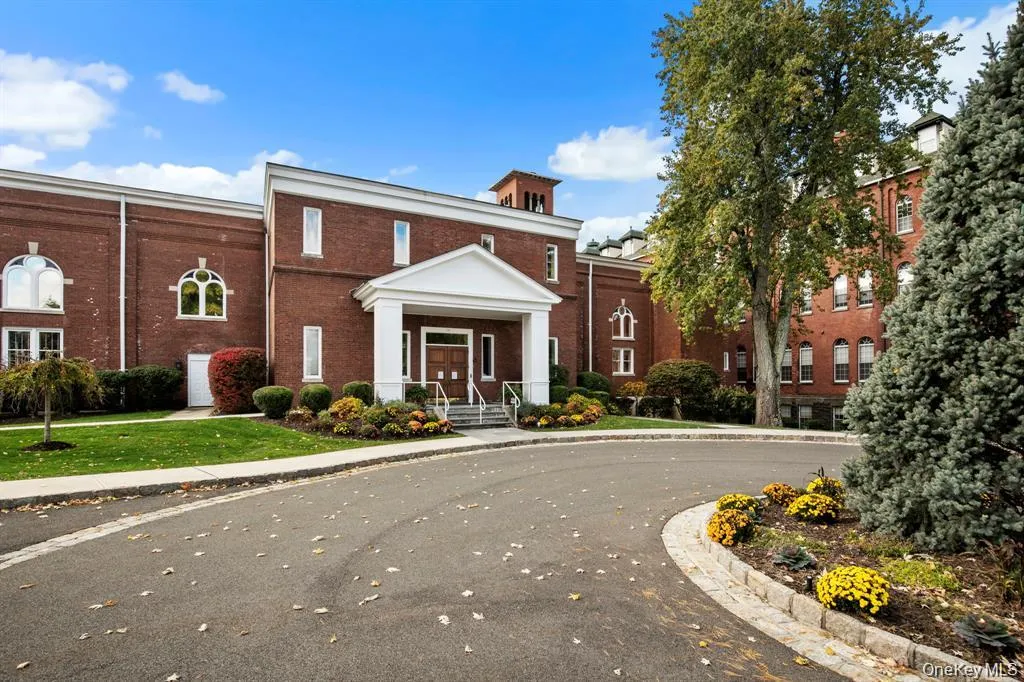 Rear view of the stately brick clubhouse surrounded by manicured landscaping and walkways leading to community amenities. Rear view of the stately brick clubhouse surrounded by manicured landscaping and walkways leading to community amenities.