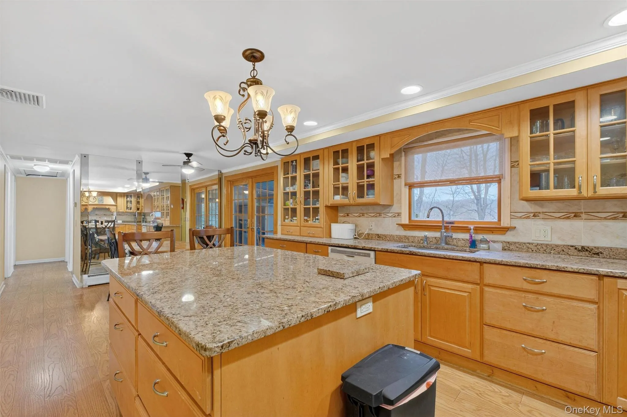 Kitchen with glass insert cabinets, light stone counters, a chandelier, recessed lighting, and crown molding Kitchen with glass insert cabinets, light stone counters, a chandelier, recessed lighting, and crown molding